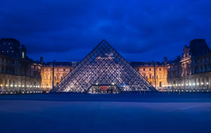 Louvre captured at night during the blue hour with the glass pyramid in the foreground.