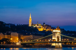 Chain Bridge at night during the blue hour with the lights glowing on the bridge and in the background.