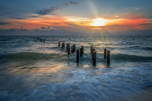 Sunset in Naples, Florida over the Gulf with the receding water and pilings from the old Naples Pier.