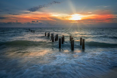 Sunset in Naples, Florida over the Gulf with the receding water and pilings from the old Naples Pier.