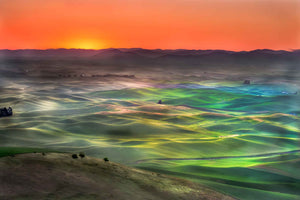 Sunrise over the Palouse with vivid orange horizon and pastel colors from reflection of light on the dew.