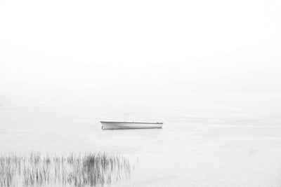 A high key image with dreamy scene of a small bot anchored in calm water.