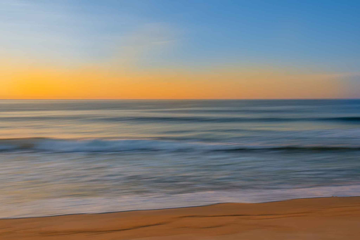 An abstract dreamy image on the beach at sunrise with gold color on the horizon and gentle waves.