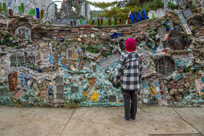 Girl with pink hair staring at mosaic wall in Philadelphia.