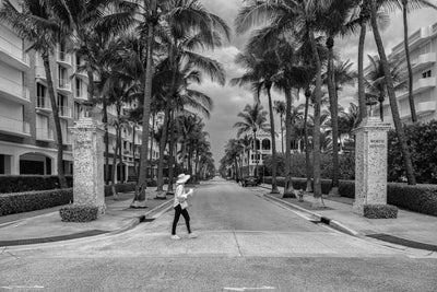 Black and white image looking down Worth Avenue in Palm beach with a woman walking across the street.