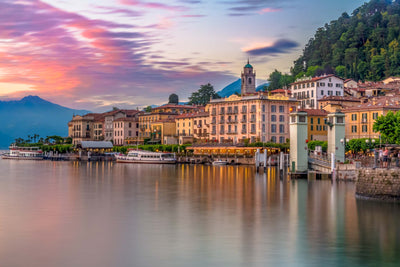 Bellagio on Lake Como at dusk with hues of pink, orange, and yellow in the sky.