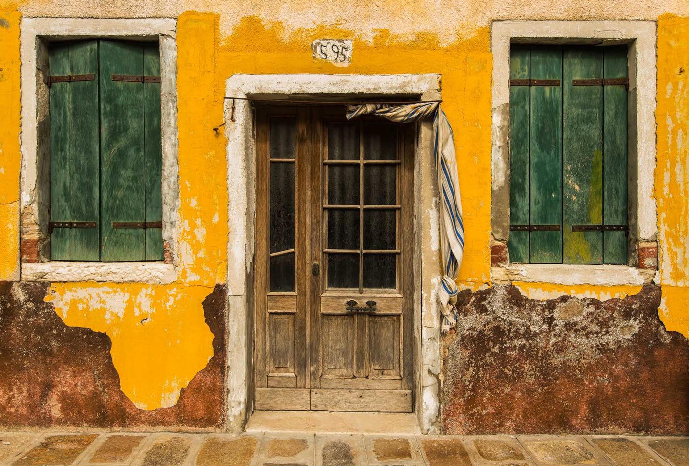 Old weathered  building painted yellow in Burano, Italy
