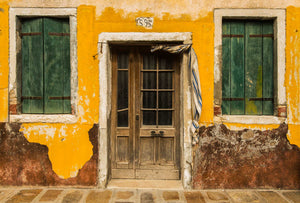 Old weathered  building painted yellow in Burano, Italy